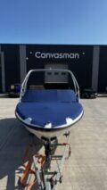 Blue bow-over-screen cockpit tonneau cover fitted to a motorboat